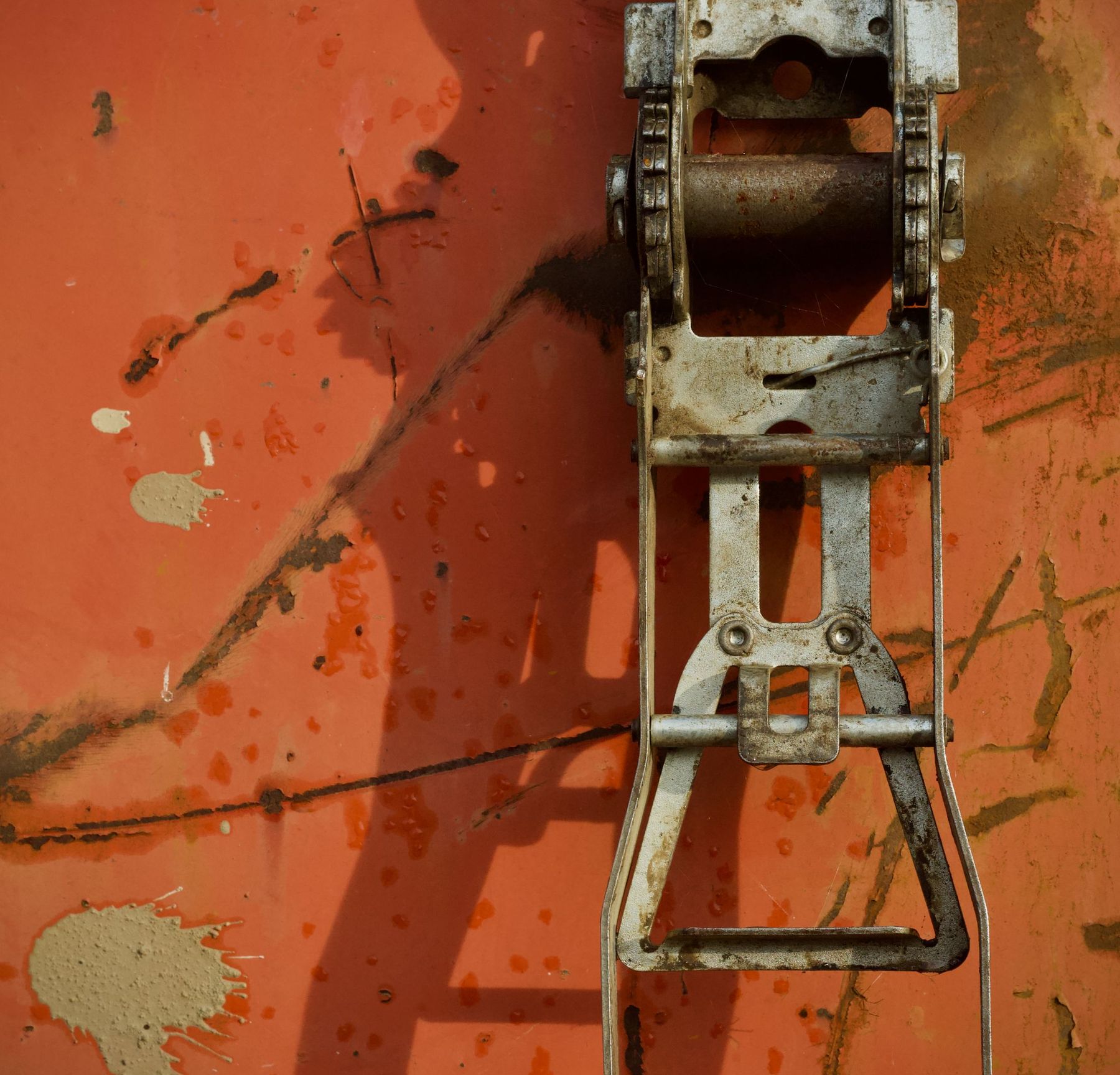 A ratchet strap on weathered orange steel